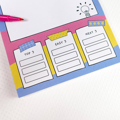 Colourful ADHD A5 brain dump notepad zoomed in on task lists and a pink pen on a white background