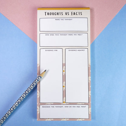 ADHD thoughts vs facts notepad with on a pink and blue background and a patterned pencil