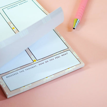 ADHD thoughts vs facts notebook with a tear-out page on a pink background, with pink pen