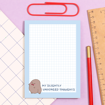 Notebook with grid paper and cartoon character on a pink and purple background with stationery items.